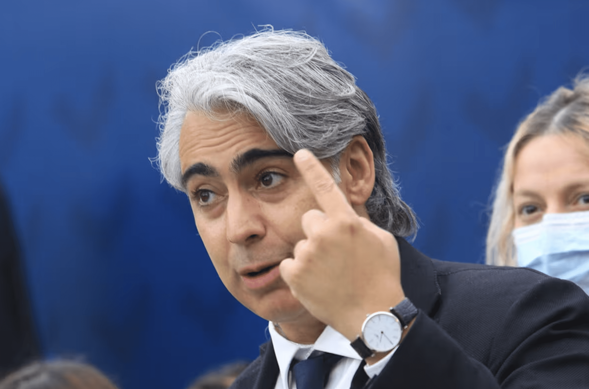 Marco Enríquez Ominami en un debate. Fondo azul, mano izquierda levantanda.